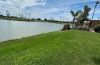 Green common-area lawn beside a community lake, with palms and the city skyline beyond
